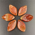Macro view of six hand-carved orange red agate leaf pendants with detailed veins - Red Agate