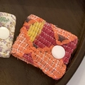 Floral and knitted fabric cable organizers with white snap buttons on wood surface - Orange Diamond Jacquard
