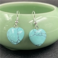 Detail of heart-shaped turquoise stone earrings hanging on a green ceramic bowl - Blue Turquoise