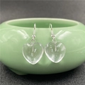 Close-up of heart-shaped crystal drop earrings hanging on a green ceramic bowl rim - White Crystal