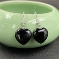 Polished black heart-shaped stone earrings on a green ceramic bowl for display - Black Agate