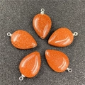 Detail view of five teardrop-shaped orange sandstone pendants with silver metal loops - Goldstone (Synthetic)