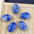 Faceted oval blue sodalite pendants with gold and silver metal bails on bamboo mat - Blue Spot Stone