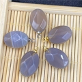 Detailed view of oval agate pendants with geometric carvings on a bamboo mat background - Grey Agate