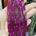 Dettaglio macro di perle di agata cilindriche rosso rosa con trame naturali - Agata Rosso Rosa
