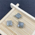 Dettaglio di tre ciondoli in quarzo rosa a forma di quadrifoglio su vassoio bambù - Pendaglio di Labradorite