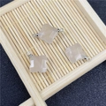 Macro detail of rose quartz clover pendants with silver loops on a bamboo tray - White Agate Pendant