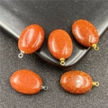 Macrodetail van ovale goudsteen hangers met glinsterende deeltjes en metalen oogjes - Goudsteen Met Gouden Clip (Synthetisch)