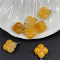 Detailed macro view of yellow chalcedony four-leaf clover charms on a white shell tray - Topaz