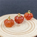 Detailed view of three orange quartz pumpkin charms with gold clasps on wood - Red Agate