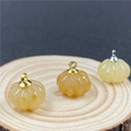 Macro detail of pumpkin pendants with metal clasps on natural wood slice base - Topaz