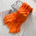 Écharpe légère en coton et lin orange vif avec bords effilochés sur un panier noir - Orange