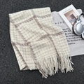 Thick plaid scarf in beige and brown check with soft fringe details laid on a street background - Beige