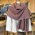 Red-brown plaid knit scarf with fringes paired with light beige wool coat in cafe - Red