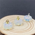 Macro detail of opalite pumpkin pendants with gold and silver metal rings on wood - Opalite