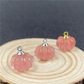 Vista macro di ciondoli a forma di zucca in quarzo fragola rosa su base in legno - Rosso Anguria (Sintetico)