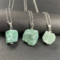 Detalle macro de tres colgantes de piedra natural verde en bruto con cadenas plateadas - Amazonita