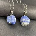 Macro shot of irregular deep blue lapis lazuli raw stone pendants on silver chains - Lapis Lazuli
