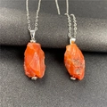 Macro detail of natural irregular orange raw gemstone pendants on silver chains - Red Agate