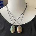 Detail van twee ovale abalone schelpkettingen met iriserende textuur op een etalagepop - 45-55mm Abalone Schelp (Dubbelzijdig)