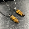 Close-up of hexagonal tiger eye crystal pendants on black cord with metallic clasp - Tiger's Eye