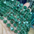 Close-up of hand holding faceted bicone light green agate beads with clear seed spacers - 1 Strand Green Aventurine