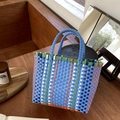 Close-up of blue and orange hand-woven basket bag on a wooden table with lifestyle decor - Blue Color Blocking