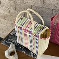 Détail d'un sac tressé en PVC avec rayures colorées et boucles en métal argenté - Blanc Cassé