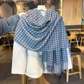 Weicher karierter Schal in Blau und Braun mit Fransen über einem beigen Wintermantel - Blau