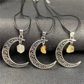 Detailed macro view of silver hollowed crescent moon pendants with raw yellow crystal stones - Citrine
