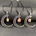 Close-up of three vintage hollow moon pendants with raw orange crystal on black cords - Sunstone