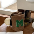 Brown plush bucket bag with green M embroidery on a wooden table setup - Khaki