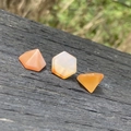 Piedras de cornalina naranja pulidas en forma de pirámide y hexágono sobre madera - Ágata roja
