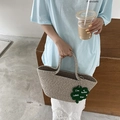 Detalle de bolso de paja tejido a mano en beige con colgante de trébol de la suerte - Gris claro