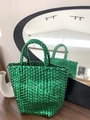 Detail of emerald green woven basket bag with metallic finish and textured handles - Green