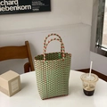 Detail of red and green plaid woven PVC tote bag placed in a lifestyle setting - Green Orange