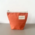 Orange canvas makeup bag with white 'nice to meet you' label and silver zipper - Watermelon red