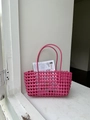 Dettaglio della borsa a cesta intrecciata rosa acceso su un davanzale bianco - Rosa Rosso
