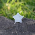 Estrella de cristal de cuarzo blanco pulido sobre una piedra natural oscura texturizada - Cristal de roca