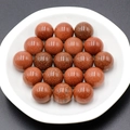 Polished 16mm goldstone round beads with metallic shimmer in a white ceramic dish - Goldstone (Synthetic)