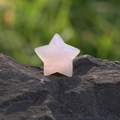 Estrella de cuarzo rosa natural pulida a mano colocada sobre una roca gris oscuro - Cuarzo rosa