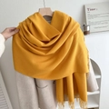 Bright yellow knitted tassel scarf shown hanging on a beige wool coat for winter fashion - Ginger Yellow No. 9