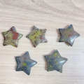 Five star-shaped dragon blood jasper stones with polished textures on wood background - Bloodstone