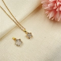 Star-shaped gold necklace with clear quartz pendant on beige fabric background - White Crystal