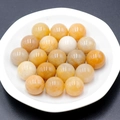 Polished 16mm natural yellow agate and white stone round beads in a white ceramic dish - Topaz