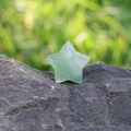 Handcrafted 30mm green aventurine star stone displayed on a natural grey rock - Green Aventurine