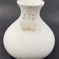 Elegant silver earrings with white crystal cross pendants on a ceramic vase - Agate