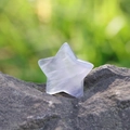 Handcrafted 30mm purple fluorite star stone ornament placed on a natural rock surface - Fluorite