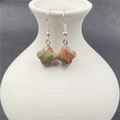 Unakite four-leaf clover drop earrings with silver hooks shown on a white ceramic vase - Unakite 1 Pair