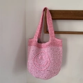 Pink handmade crochet mini tote bag with a woven smiley face and striped lining - Pink